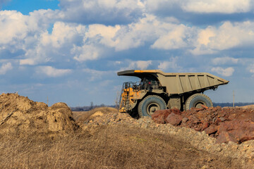 Huge yellow mining dump truck working in iron ore quarry. Mining industry