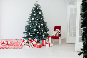 The interior of the white room with a blue Christmas tree with red gifts for the new year decor winter postcard