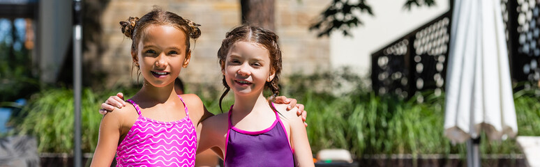 horizontal concept of girls in swimsuits embracing and looking at camera