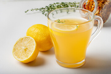 Sweet fruit and herbal tea in a transparent Cup on a light background with lemon.