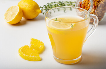 Sweet fruit and herbal tea in a transparent Cup on a light background with lemon.