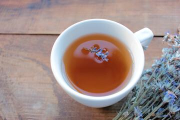 Cup of herbal tea with lavender flowers on wooden table from above. 