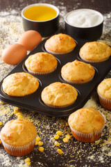 Delicious snack corn muffins in a baking dish and ingredients close-up on the table. vertical