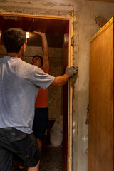 Dismantling of old entrance doors, old wooden box and door, the master cuts, cuts a wooden box from the wall with a hand saw.