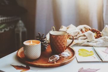 cozy autumn or winter morning at home. Still life details with cup of tea, candle, sketch book with herbarium and warm sweater. Scandinavian hygge concept