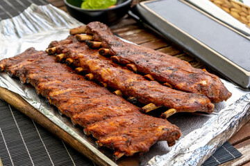 Hot, Freshly prepared, Crispy, Juicy BBQ pork ribs on wooden table. Dinner party outside at homes terrace.  Lifestyle concept.