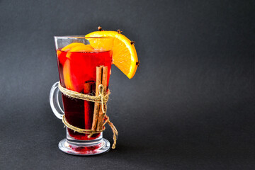 Christmas mulled wine with spices and orange on dark black background. Selective focus. Anise stars...