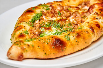 Khachapuri meat on a white plate. Close-up, selective focus