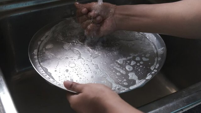 Utensils are being cleaned in running tap water inside the kitchen. Indian household and kitchen