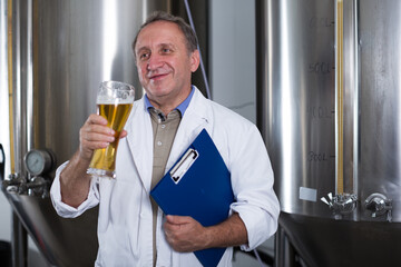 Portrait of expert with folder who is checking beer in the laboratory of the brew-house.