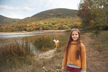 Back view of preteen female kid resting in the park at warm autumn weather.  Girl wearing fall...