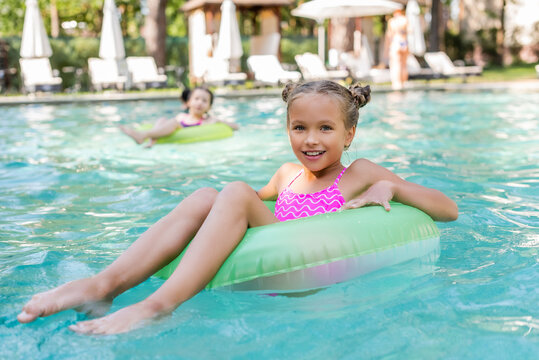 girl looking at camera while floating in pool on swim ring
