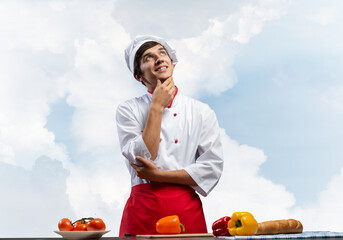 Young male chef standing with folded arms