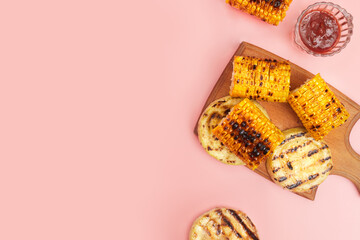 grilled vegetables corn on a pastel pink background, copies of space, flatlay