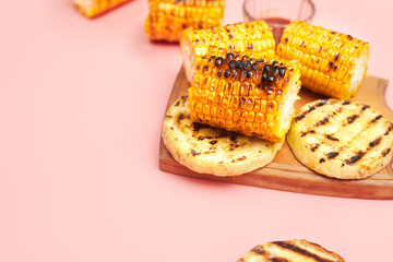 grilled vegetables corn on a pastel pink background, copies of space, flatlay