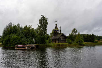 Fototapeta na wymiar wooden ancient church on the island among the trees during the rain