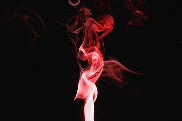 Red smoke on a black background. Colored smoke. Incense stick smoke, illuminated by red light.