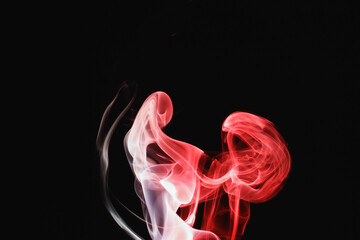 Red smoke on a black background. Colored smoke. Incense stick smoke, illuminated by red light.