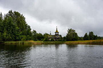 Fototapeta premium wooden ancient church on the island among the trees during the rain