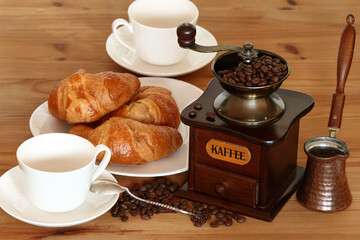 coffee still life - old coffee grinder, coffee cup, croissant, beans, cezve