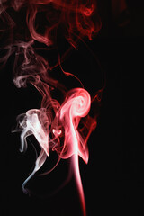Red smoke on a black background. Colored smoke. Incense stick smoke, illuminated by red light.