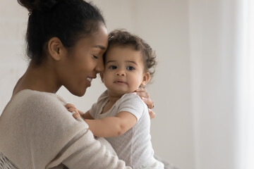 Bonding mixed race young mommy enjoying sweet tender moment with cute little toddler son or...