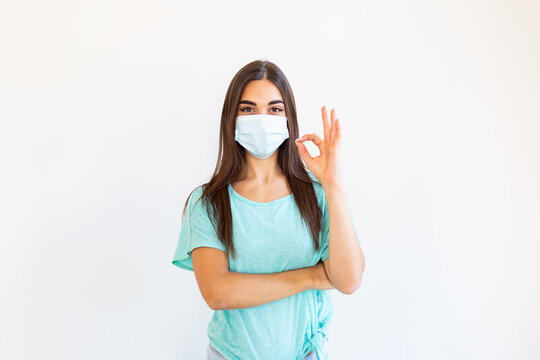 Young woman wearing medical face mask, studio portrait. Woman Wearing Protective Mask and Showing OK sign. Woman wearing surgical mask for corona virus