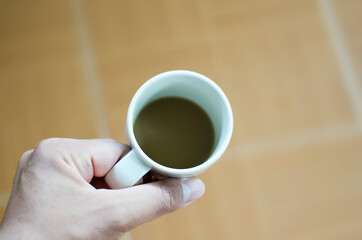 close-up of a left hand holding a cup of coffee 