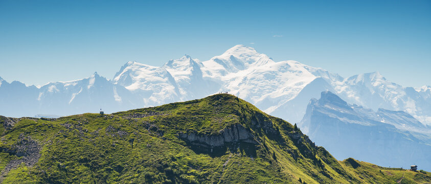 Beautiful Alpine landscape with view of snowed Mont Blanc in French Alps in Morzine area, Haute-Savoie, Auvergne-Rhone-Alpes region, France. Silhouettes of people on crest of mountain admiring view.