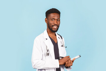 African american male doctor with stethoscope in white coat writing prescription on blue