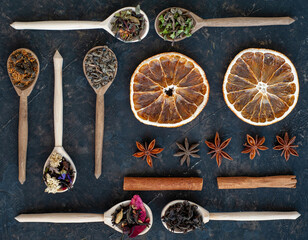 Fototapeta na wymiar Composition of different varieties of tea in wooden spoons, anise, cinnamon and dried orange. Knolling.