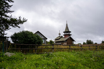 Fototapeta na wymiar wooden ancient church on the island among the trees during the rain