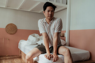 Asian gay in stripped shirt in bedroom.
