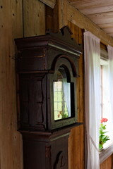Old worn tall clock with classic black numbers on cracked and ornate white dial and metal arrows.