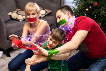 Parents with a charming seven-year-old son fool around celebrating Christmas and new year. Humor,...