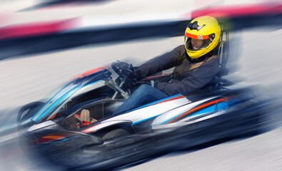 Young woman in helmet driving car for karting in sport club outdoor