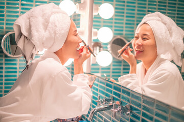 Young woman putting on makeup after shower