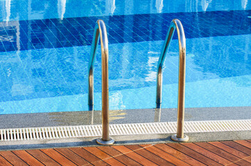 Grab bars ladder in the blue swimming pool