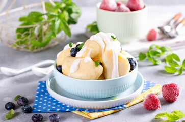 Home-cooked dumplings with cottage cheese in a bowl on white wooden background. Selective focus