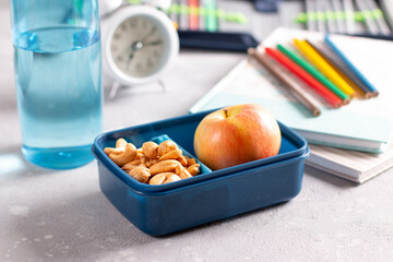 Healthy lunch box with apple and nuts on table