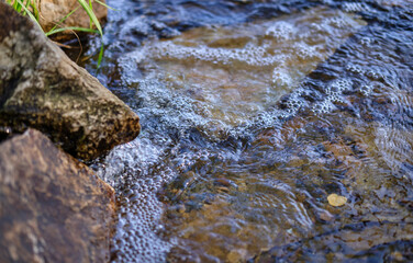 close up of water flowing into water. bubbles in water