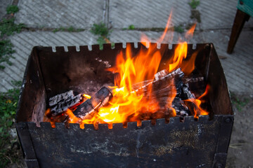 Barbecue grill mangal preparation with roaming fire outside building. Burns a firewood