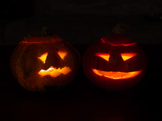 Two lighted carved pumpkins in the dark