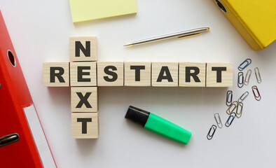 Wooden cubes with words NEXT RESTART on the office desk.