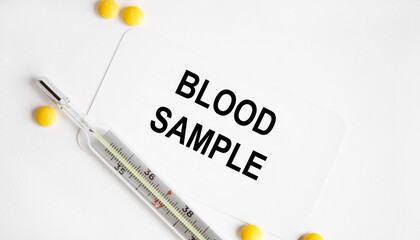 Obraz premium On the card is the inscription BLOOD SAMPLE, next to yellow tablets and a thermometer. A medical concept.