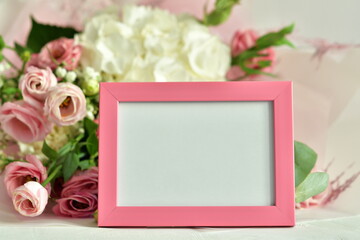 Obraz premium bouquet of delicate roses, eustoma, hydrangea and photoframe on light background.Flowers composition.Mother's Day, Valentine's Day,birthday. Copy space. I love you concept.Wedding invitation.