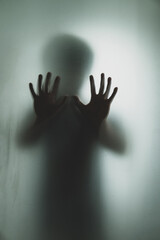 Ghost concept shadow of a men behind the matte glass blurry hand and body soft focus