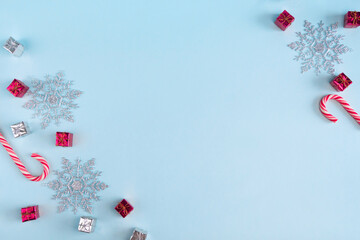 Christmas composition flatlay with snowflakes, gift boxes, candies on blue background with copy space.