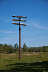 one black old wooden electric pole without wires against a blue sky
