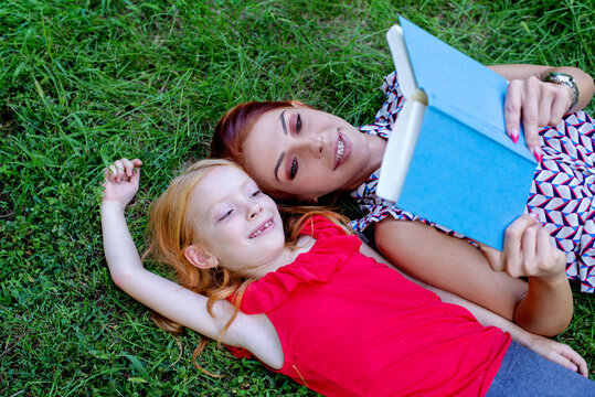 Mom and daughter  reading  book in the park